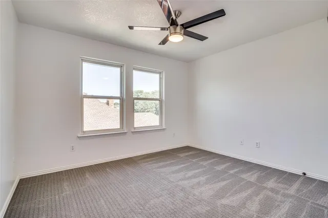 an empty room with a window and a fan