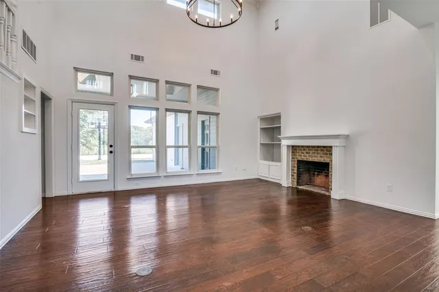 a view of an empty room with wooden floor and a fireplace