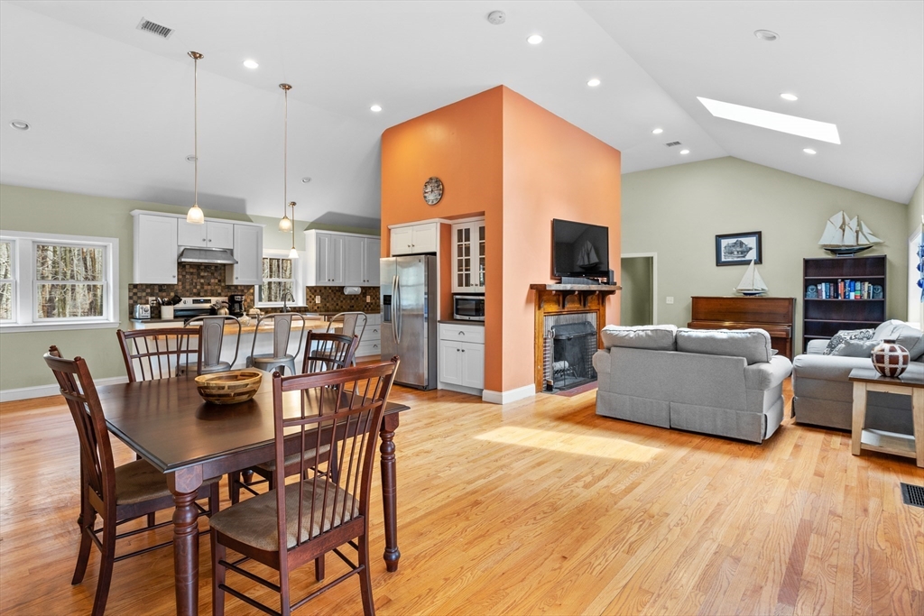 a dining room with stainless steel appliances kitchen island granite countertop a table and chairs with wooden floor