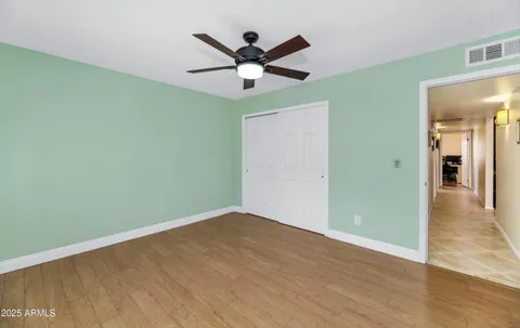 an empty room with wooden floor and ceiling fan