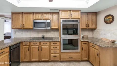 a kitchen with granite countertop white cabinets stainless steel appliances and a window
