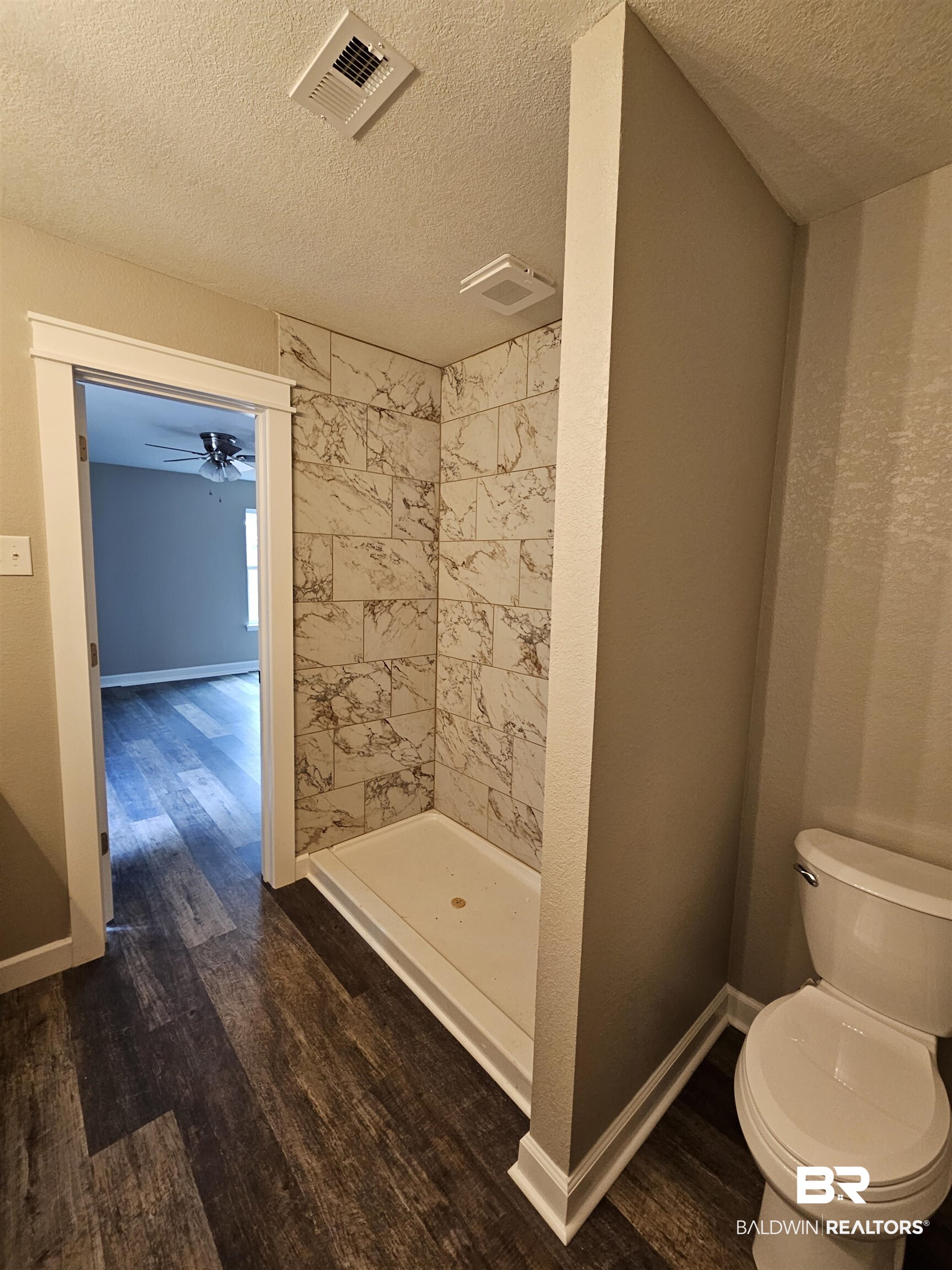 138 Wicker Way Daphne, AL 36526 - Photo 25 of 32 Full bathroom featuring dark wood-style floors, a shower stall, a textured ceiling, and ceiling fan
