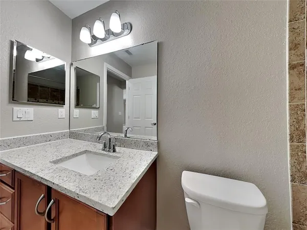 a bathroom with a granite countertop sink a toilet and mirror