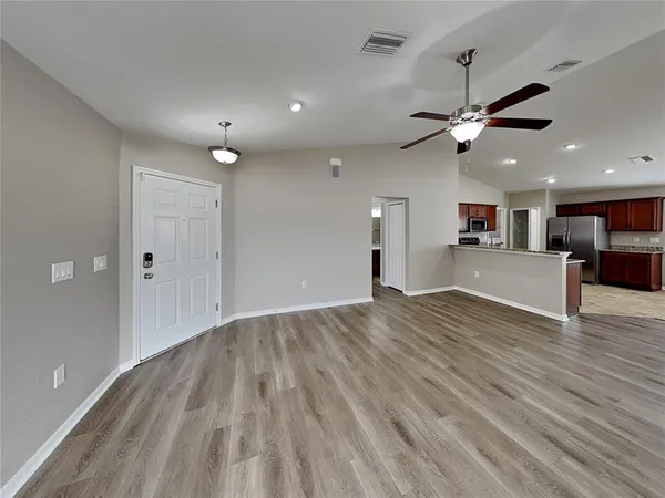 an empty room with wooden floor and a ceiling fan