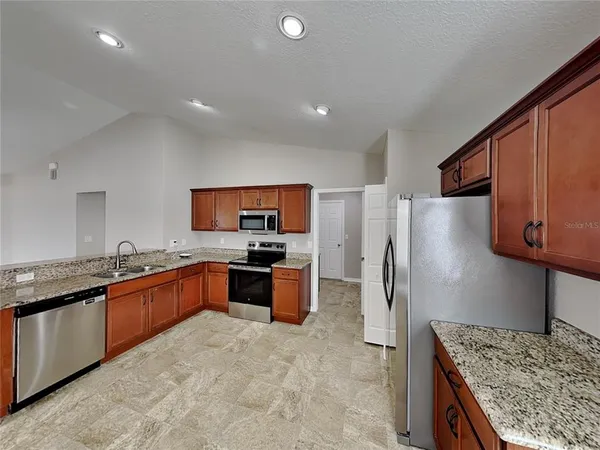 a kitchen with stainless steel appliances granite countertop a refrigerator stove and oven