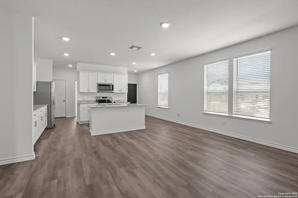 a large kitchen with stainless steel appliances granite countertop a large counter top and a wooden floors