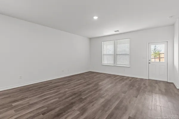 an empty room with wooden floor and windows