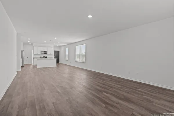 a view of a big room with wooden floor and windows