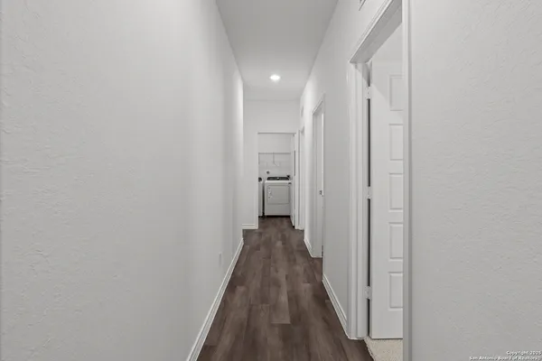 a view of a hallway with wooden floor and a bathroom