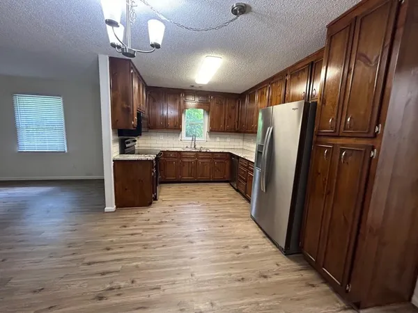 a kitchen with stainless steel appliances granite countertop a refrigerator a sink dishwasher a stove and a refrigerator