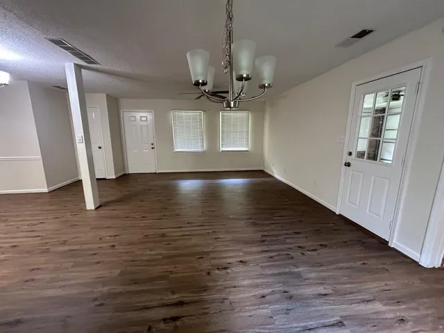 a view of an empty room with window and wooden floor