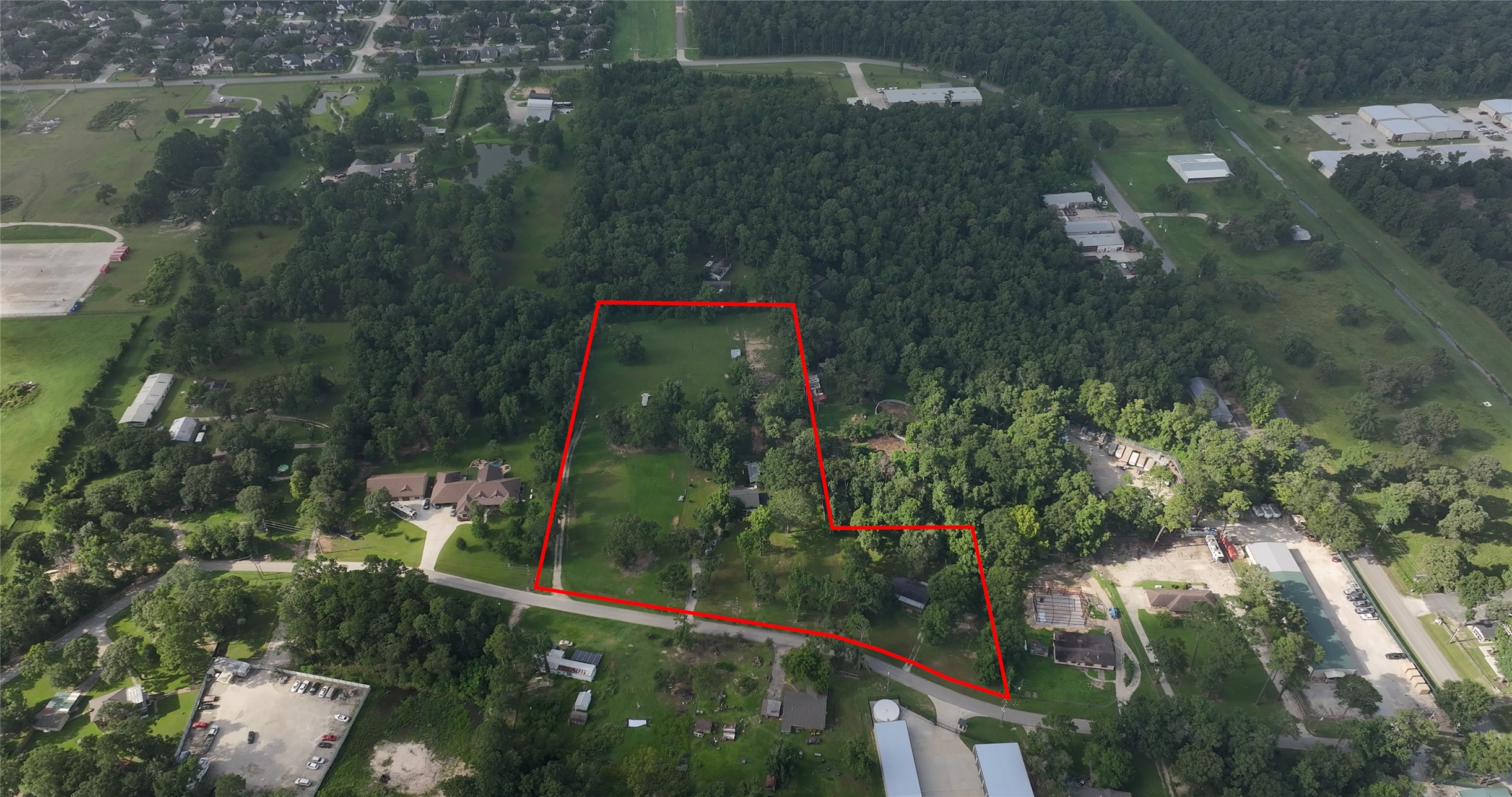 an aerial view of residential houses with outdoor space and trees