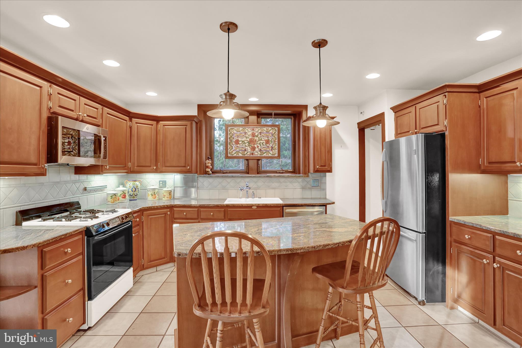 4100 Kutztown Road Temple, PA 19560 - Photo 20 of 67 a kitchen with stainless steel appliances granite countertop a stove top oven a refrigerator a sink and chairs