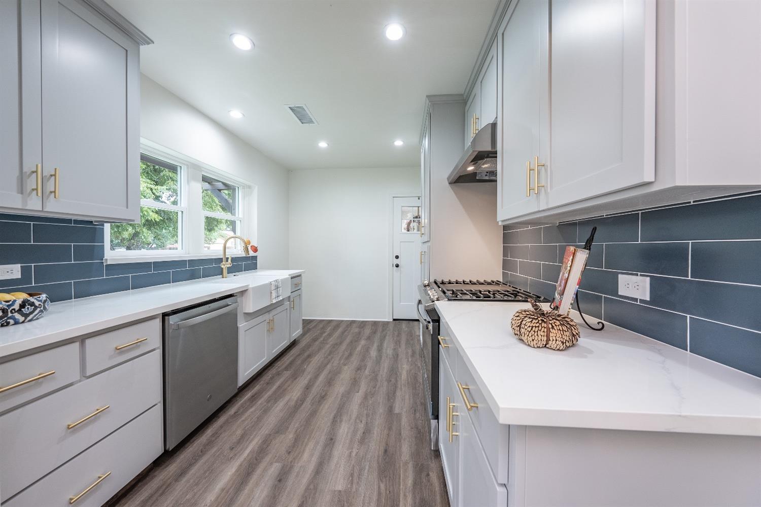 1600 West 5th Street Madera, CA 93637 - Photo 13 of 46 a kitchen with a sink a stove cabinets and wooden floor