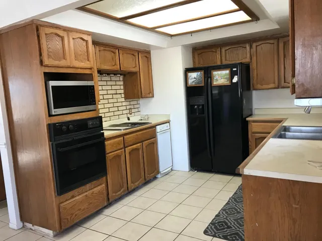 a kitchen with stainless steel appliances kitchen island granite countertop a refrigerator a stove and a sink