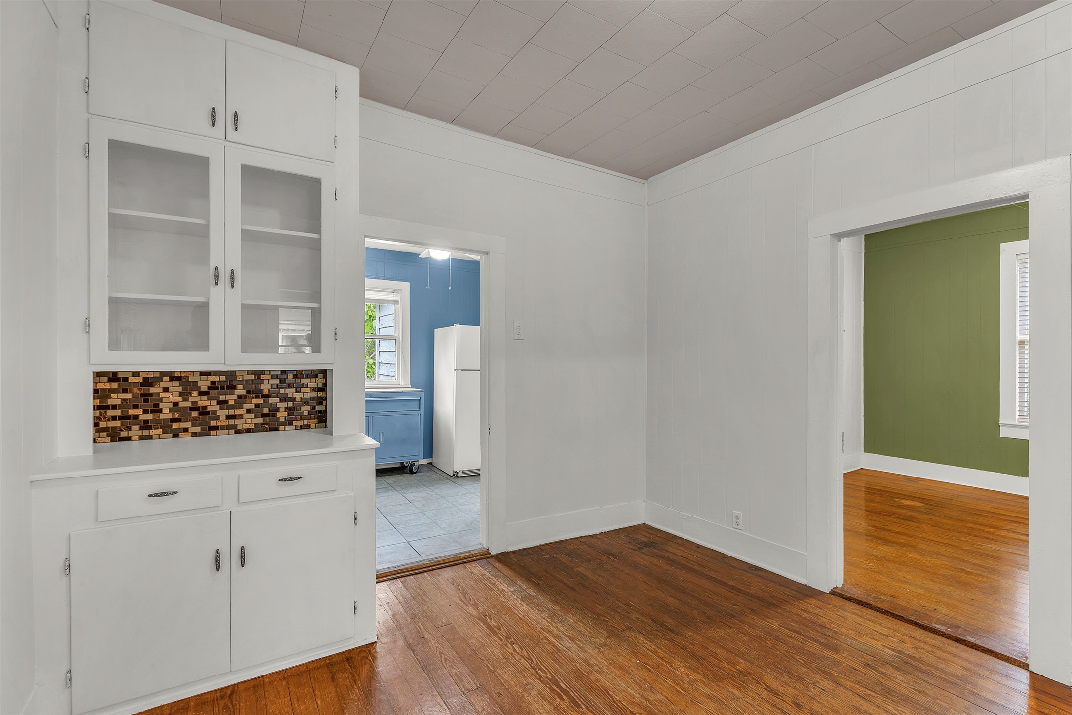 1002 Washburn Street Taylor, TX 76574 - Photo 10 of 29 This room features hardwood floors and a built-in cabinet with glass-fronted upper doors and a mosaic tile backsplash