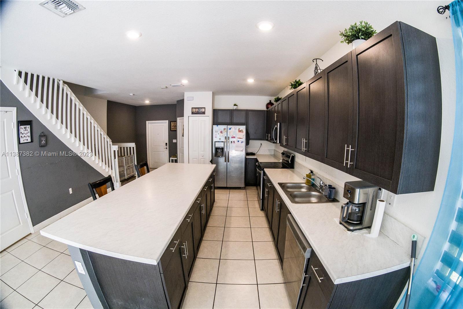 25151 Southwest 108th Court Homestead, FL 33032 - Photo 3 of 15 a kitchen with stainless steel appliances kitchen island granite countertop a refrigerator a stove and a sink with wooden floor