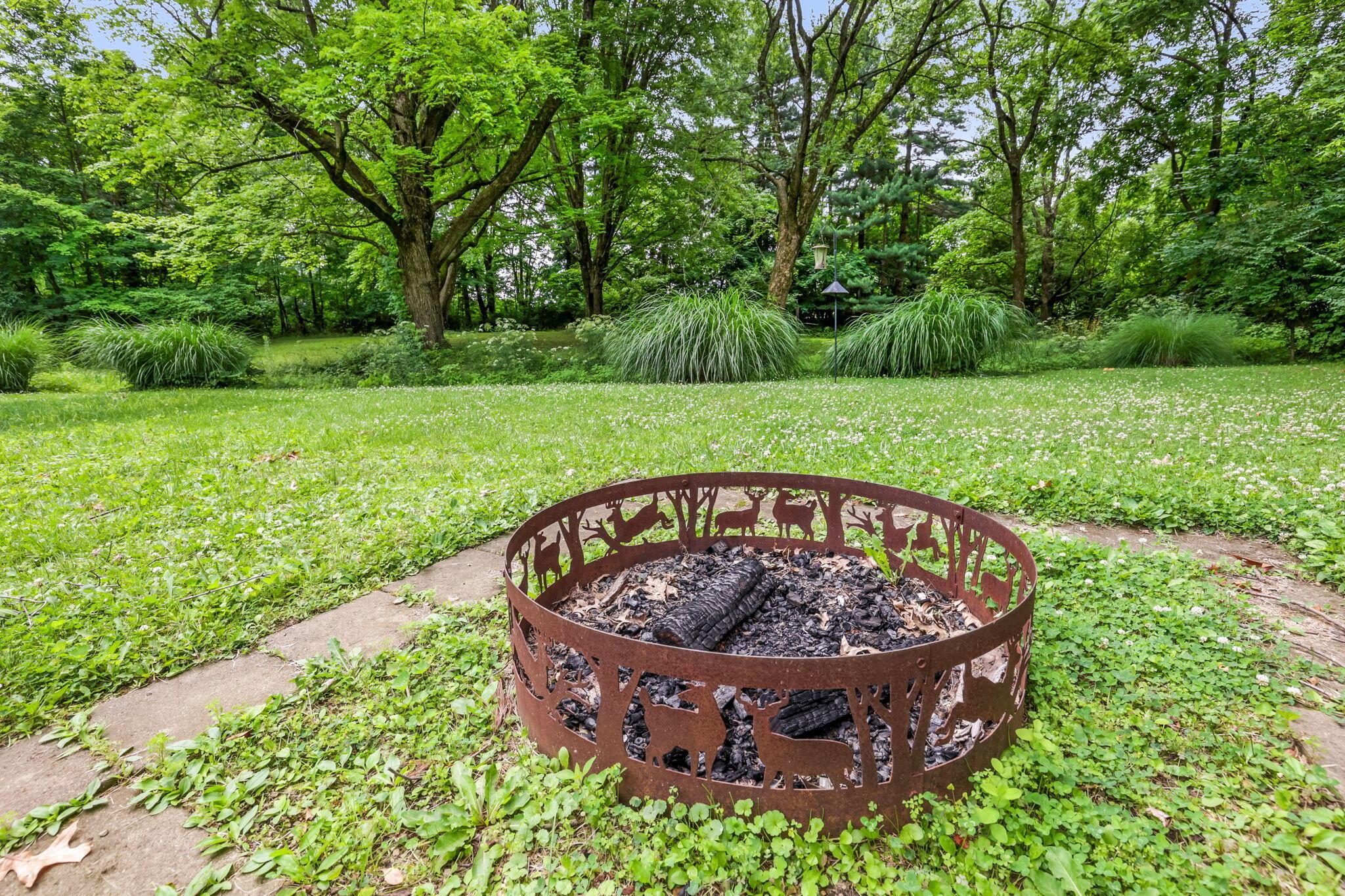 14823 Cleveland Road Southwest Pataskala, OH 43062 - Photo 42 of 57 Outdoor fire pit with decorative deer cutouts, situated on a stone patio area within a grassy lawn