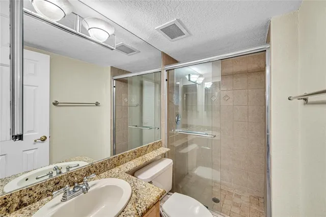 a bathroom with a granite countertop sink toilet and shower