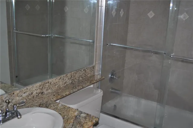 a bathroom with a granite countertop bathtub shower and toilet