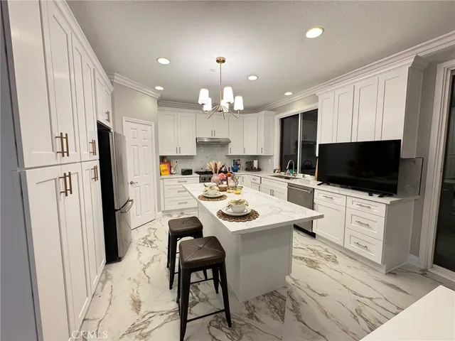 a kitchen with stainless steel appliances kitchen island granite countertop a sink and a refrigerator