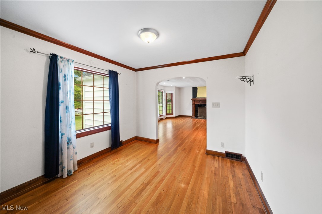 4088 Manchester Road Akron, OH 44319 - Photo 11 of 50 Unfurnished room featuring arched walkways, ornamental molding, light wood-style floors, baseboards, and a fireplace