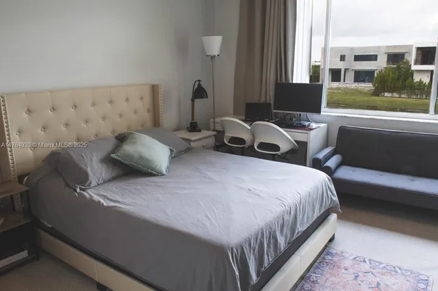 a bedroom with bed and a couch next to a window