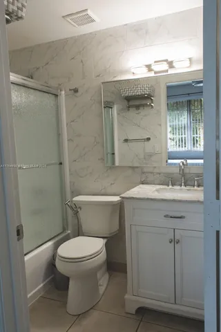 a bathroom with a granite countertop toilet a sink and a bathtub