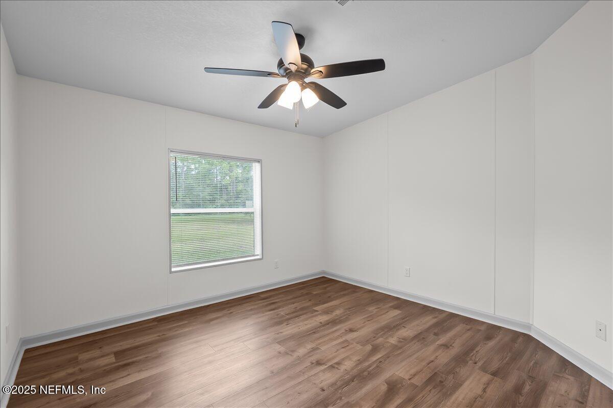 2929 Persimmon Street Bunnell, FL 32110 - Photo 16 of 28 an empty room with wooden floor fan and windows