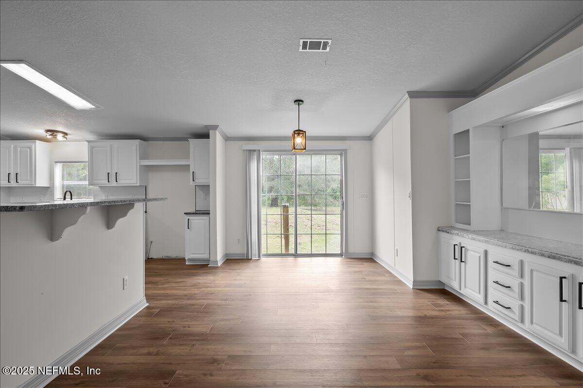 2929 Persimmon Street Bunnell, FL 32110 - Photo 4 of 28 a open kitchen with granite countertop a stove top oven a sink dishwasher and white cabinets with wooden floor