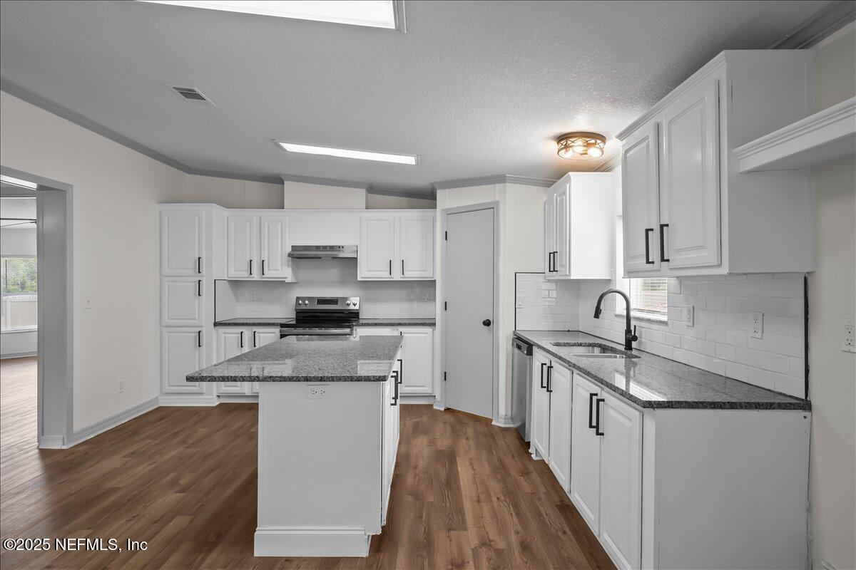 2929 Persimmon Street Bunnell, FL 32110 - Photo 6 of 28 a kitchen with stainless steel appliances granite countertop a sink stove and refrigerator