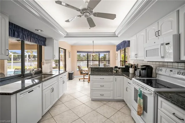 a large white kitchen with stainless steel appliances granite countertop a stove and a sink
