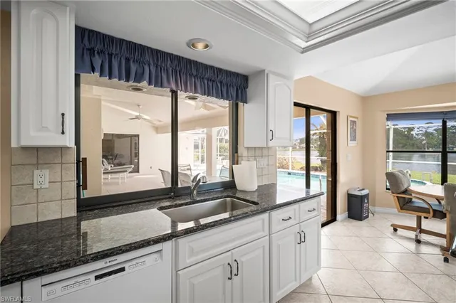 a large white kitchen with a large window and stainless steel appliances