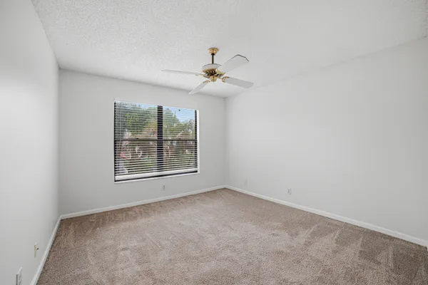 an empty room with windows and fan