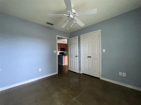 an empty room with chandelier fan and closet area