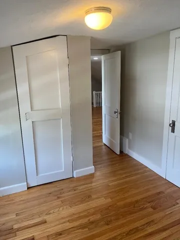 a view of an empty room with wooden floor and a bathroom