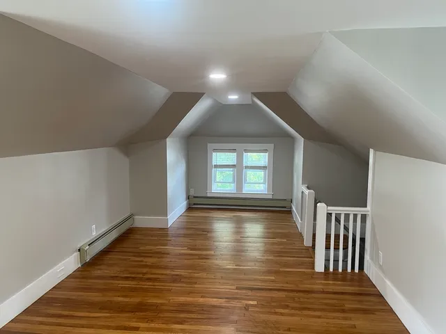 a view of an empty room with window and wooden floor