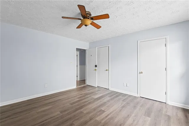 a view of empty room with wooden floor and ceiling fan