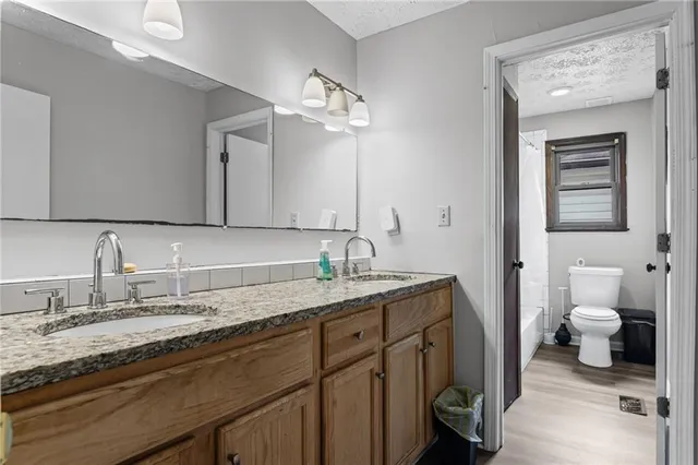 a bathroom with a granite countertop sink a toilet and a mirror