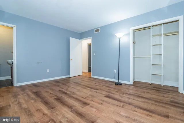 a view of an empty room with wooden floor and closet