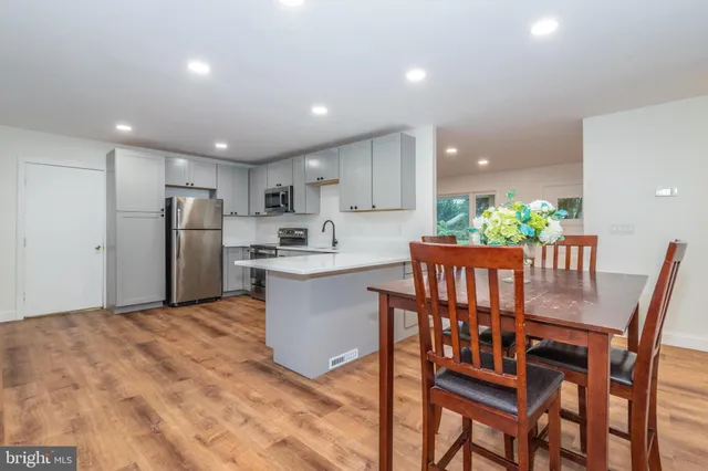 a kitchen with stainless steel appliances kitchen island granite countertop a refrigerator a stove a microwave oven with a dining table and chairs