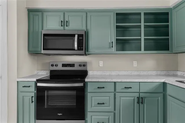 a kitchen with granite countertop cabinets stove and microwave