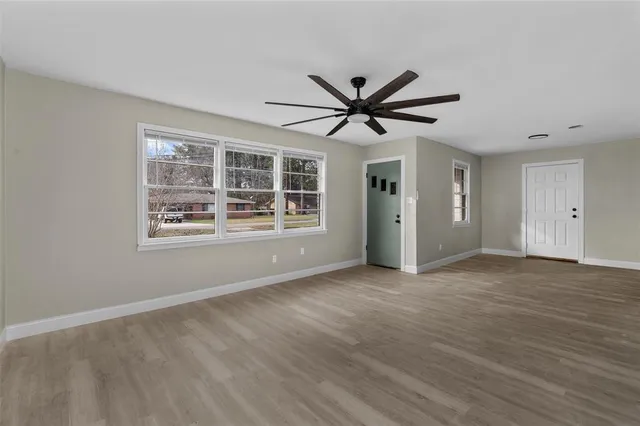 an empty room with wooden floor and windows