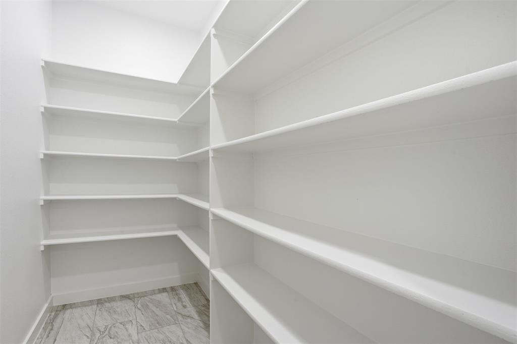 532 Highview Court Godley, TX 76044 - Photo 11 of 39 Corner pantry featuring extensive white shelving, white walls, white baseboards, and grey patterned tile flooring