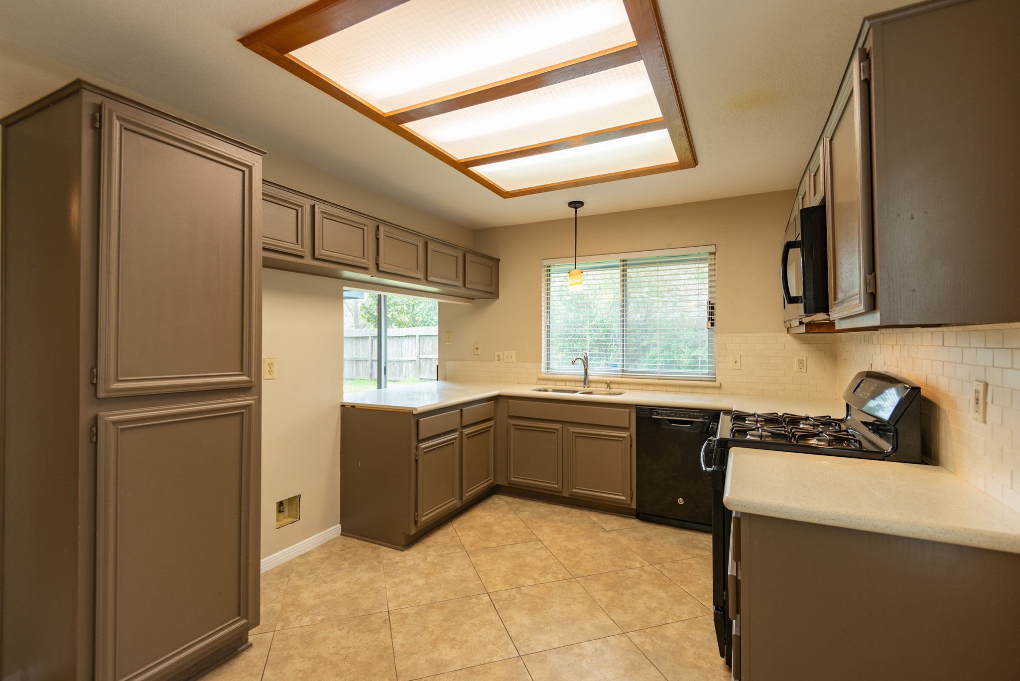 12034 Paddock Way Houston, TX 77065 - Photo 5 of 19 Kitchen features neutral quartz countertops, oven with microwave above, and a deep sink.