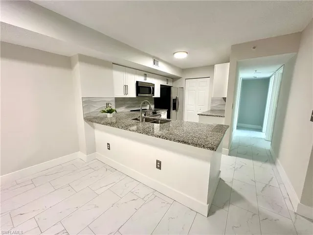 a kitchen with stainless steel appliances granite countertop a sink and a white cabinets