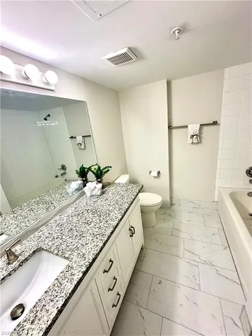 a spacious bathroom with a granite countertop sink a toilet and a mirror