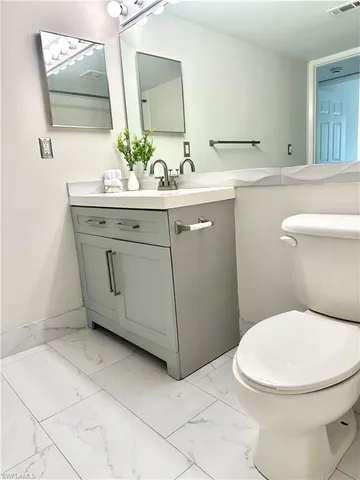 a bathroom with a granite countertop toilet a sink and a mirror