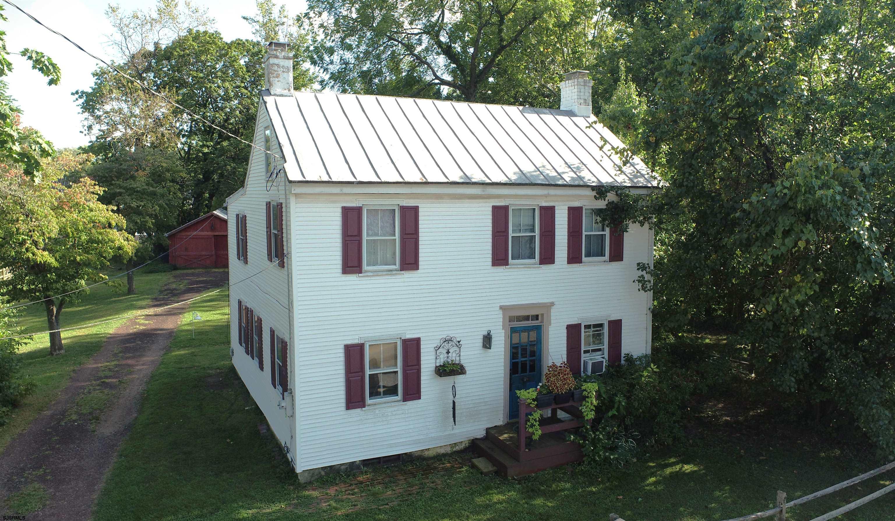 a view of a white house next to a yard with big trees