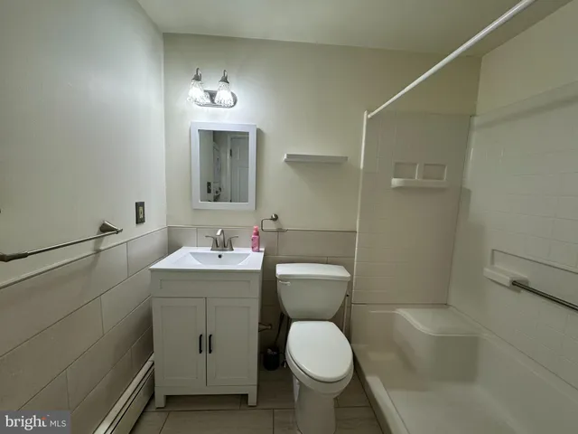 a bathroom with a toilet sink vanity granite and shower